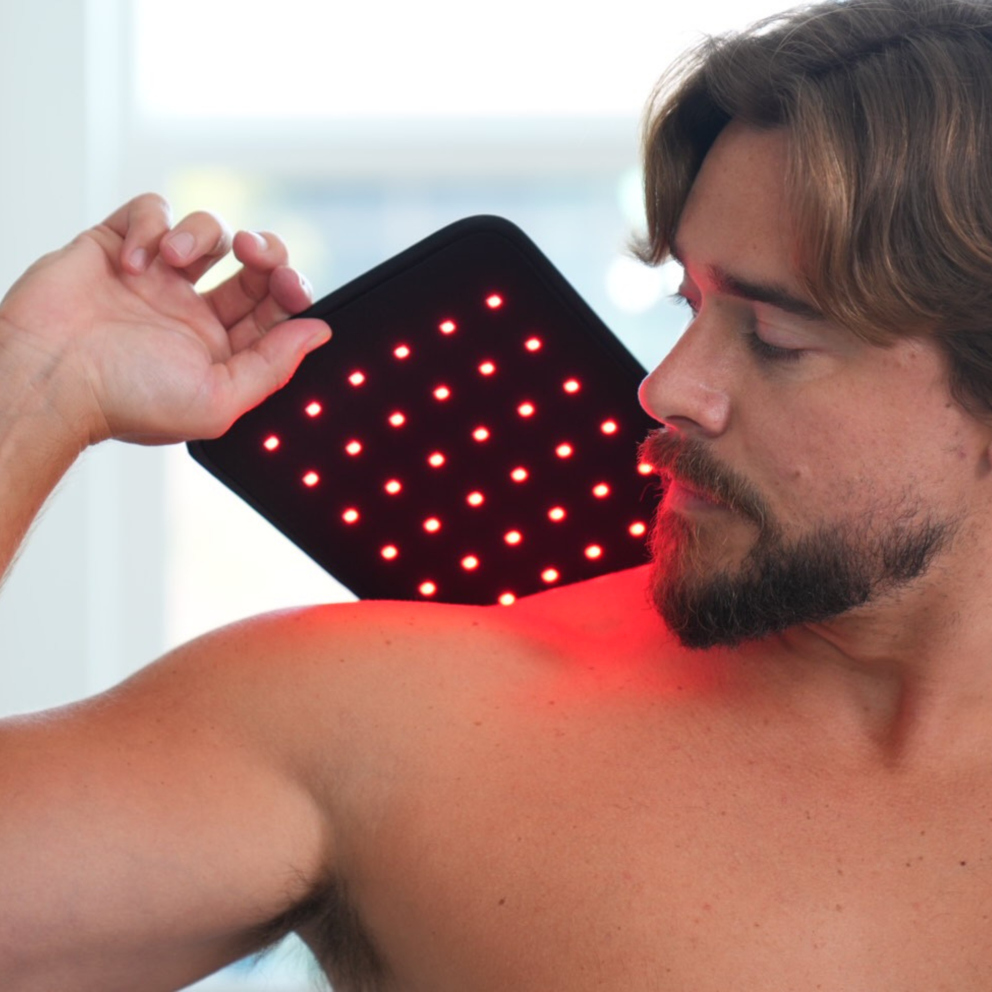 Man using a Fringe red light therapy wrap on his shoulder